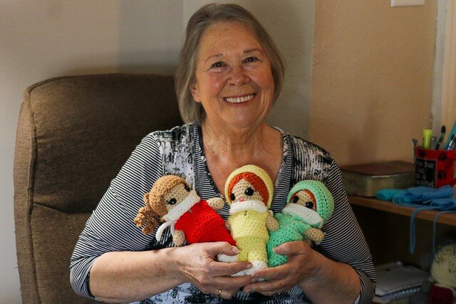 Carol Brown holding three crochet dolls