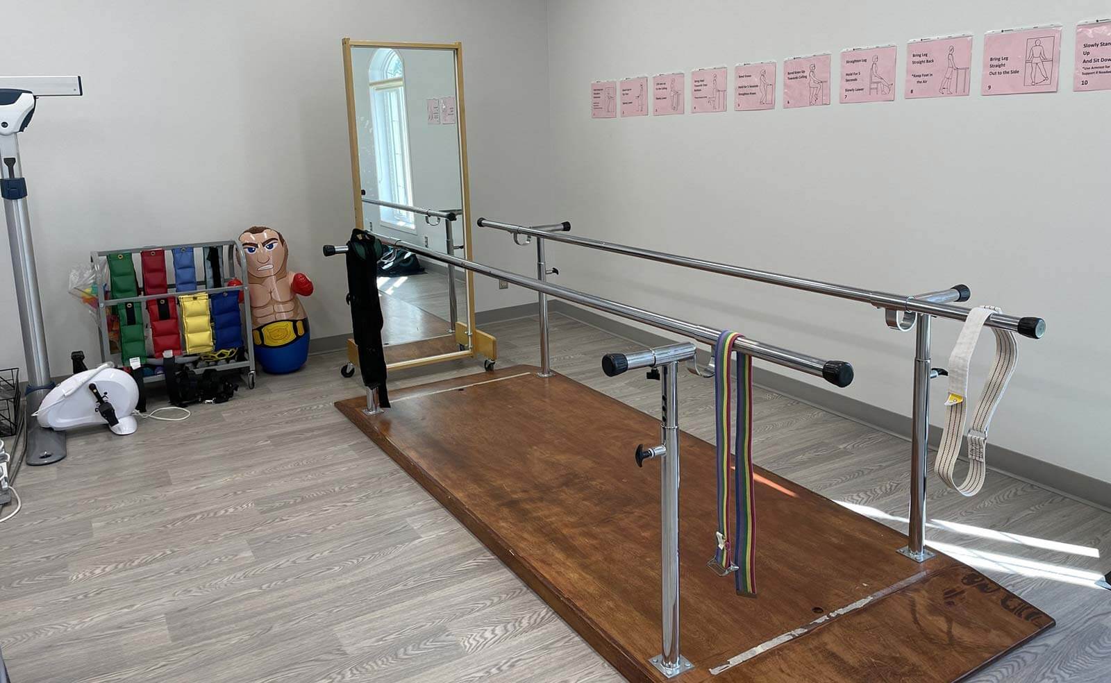 A room with a mirror and various exercise equipment, including parallel bars