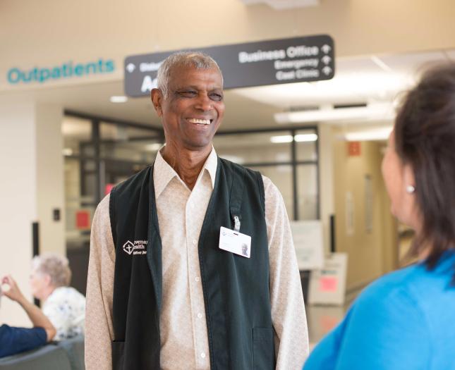 A volunteer greets a patient in a Covenant Health hospital lobby.