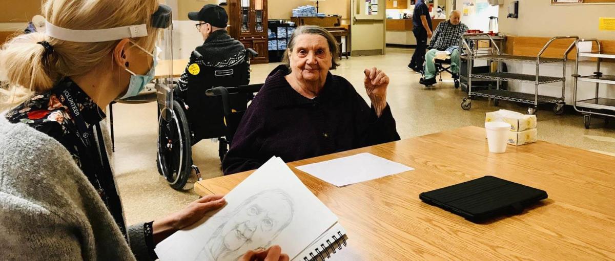 Resident Darlene Duff sits as recreation therapy assistant Jennie Vegt sketches her portrait