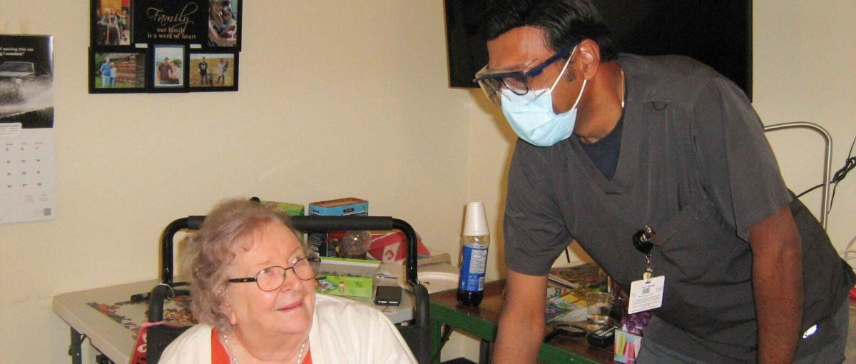 Health care aide Benny Mathew chats with a resident