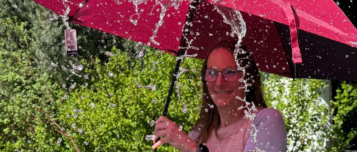 Lady under a red umbrella with water splashing the umbrella