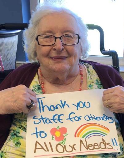 A resident holds up a colourful sign she made that says, "Thank you staff for attending to all our needs"