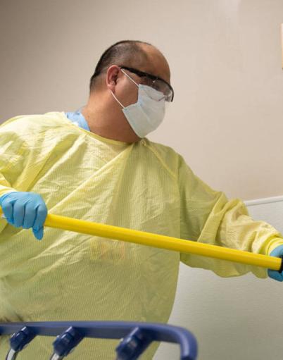 Housekeeping staff mops a wall in a hospital