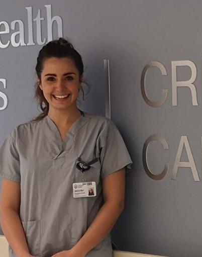 Registered nurse Jennifer Hamilton in front of signage for the Grey Nuns Hospital's Critical Care and Cardiac Sciences unit
