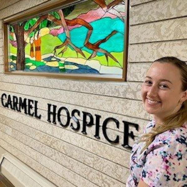 Christina poses near a stained glass window on Carmel Hospice.