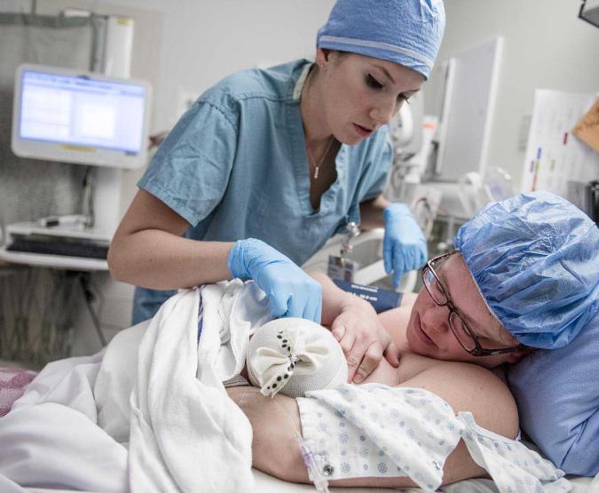 A nurse helps a mother breastfeed her newborn shortly after birth.