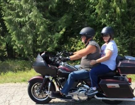 Joyce Morrison sits behind her son on a motorcycle during a sunny day